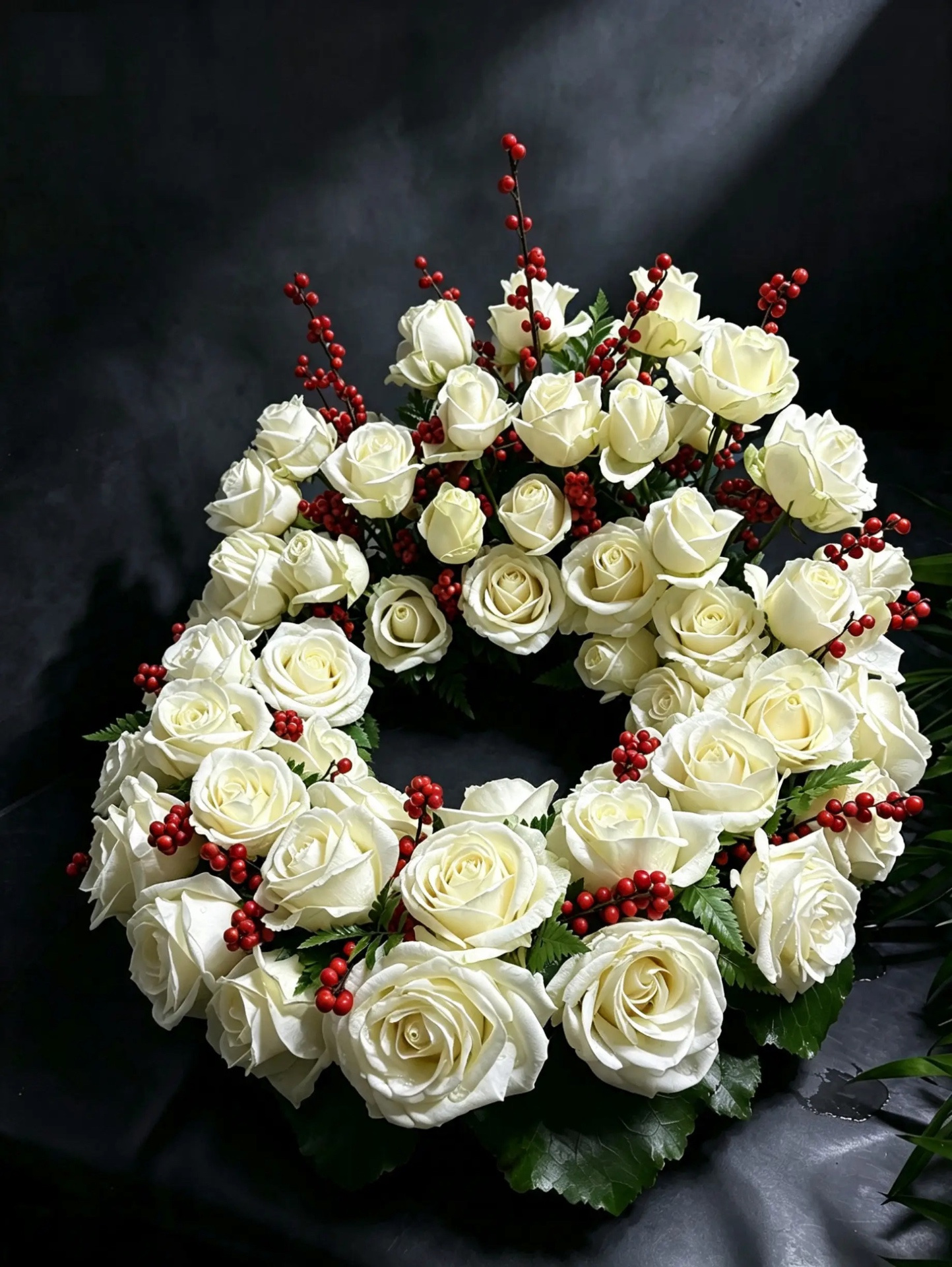 Erhöhter Urnenkranz aus weißen Rosen und roten Beeren ohne Urne