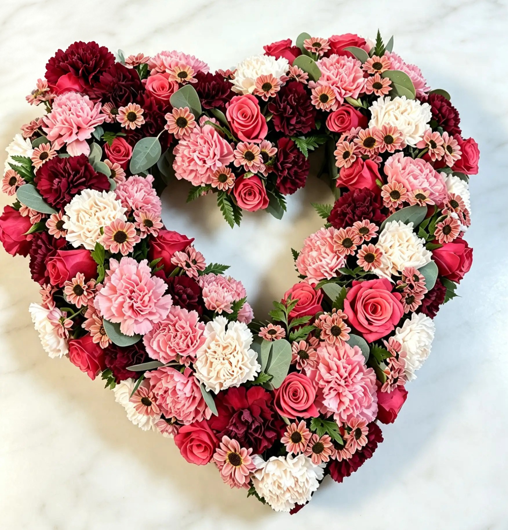 Herz aus roten und weißen Rosen mit beschrifteter Schleife