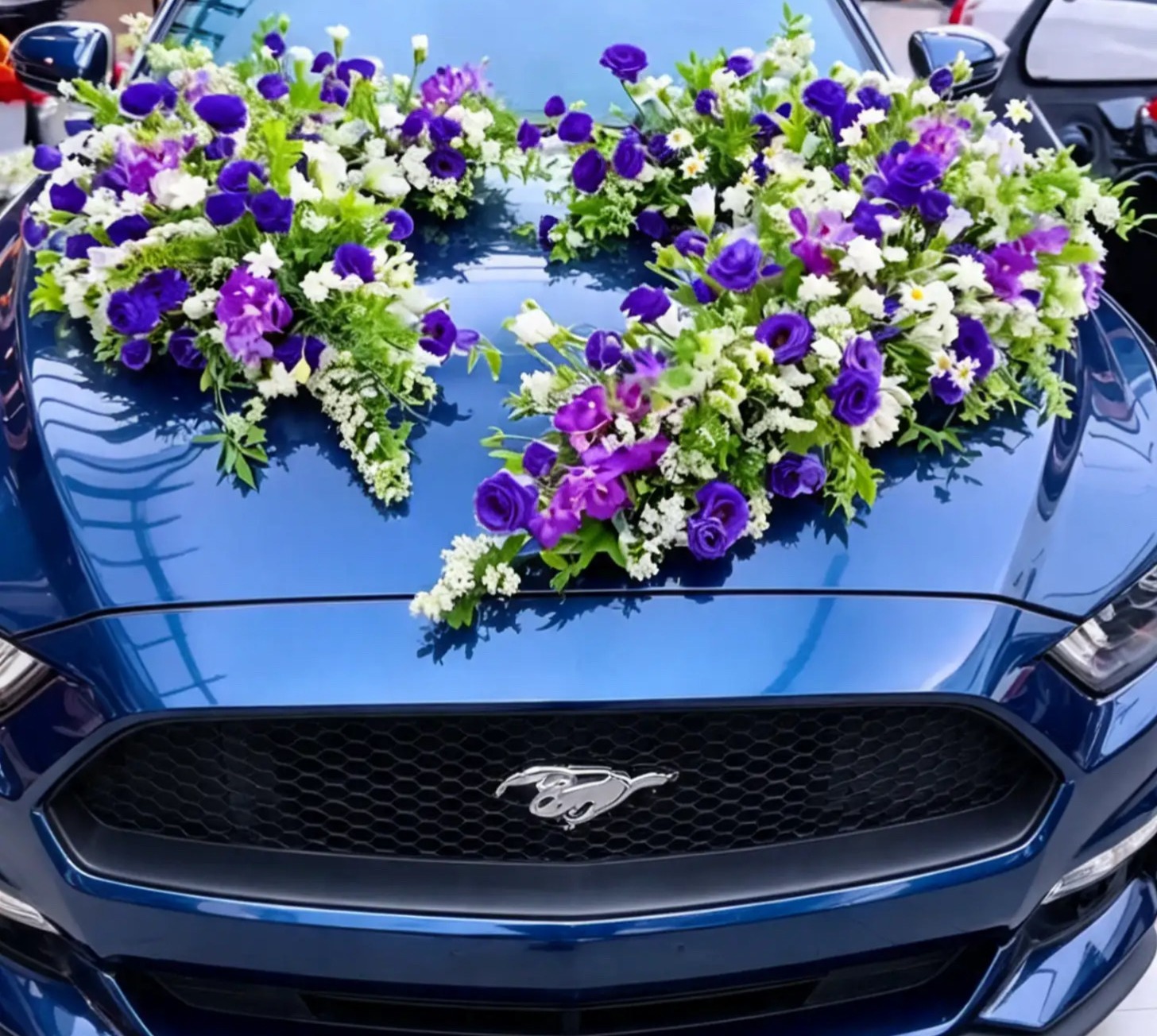 Großes violett-weißes Blumenherz auf einer blauen Motorhaube