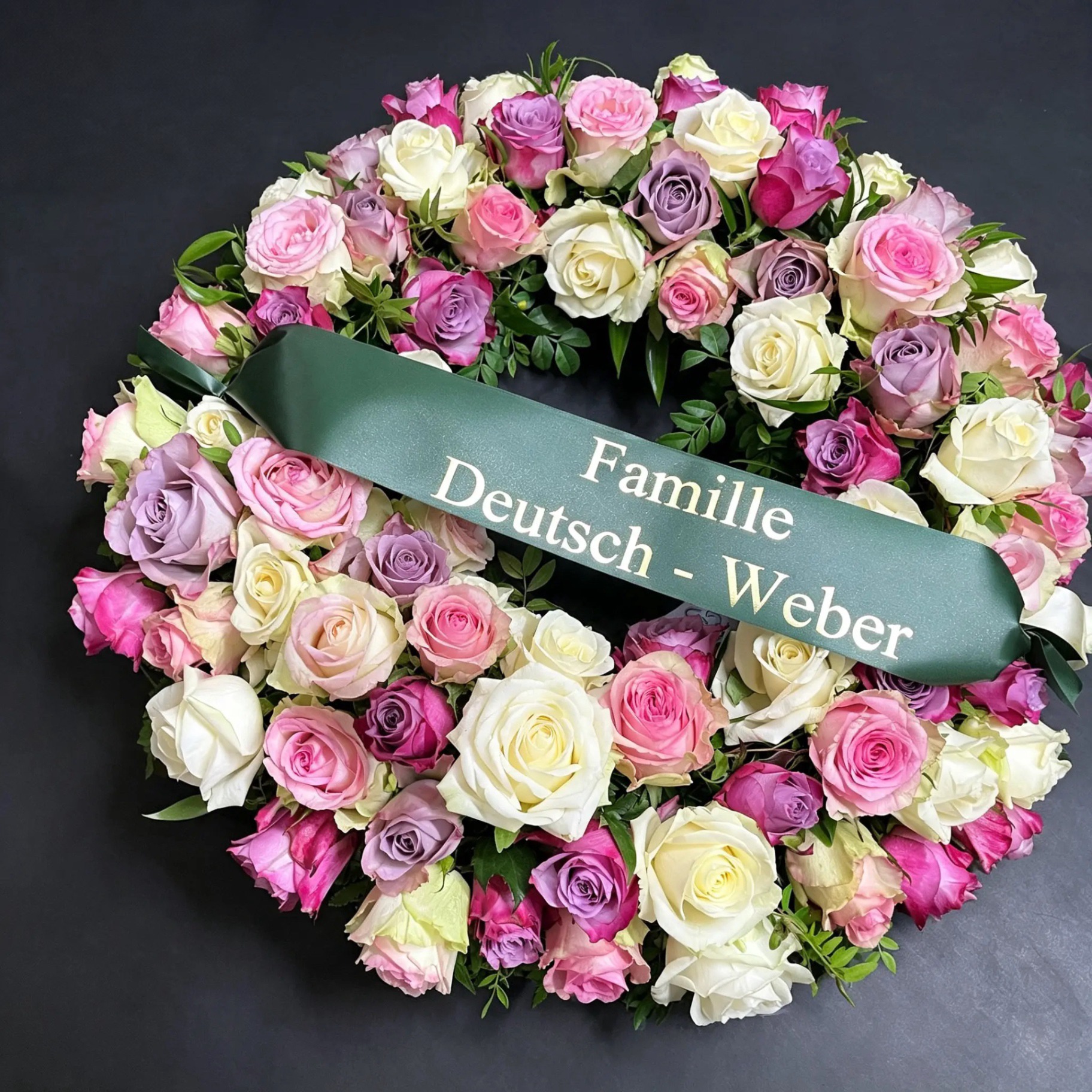 Trauerkranz in Rosa und Lila mit beschrifteter Schleife