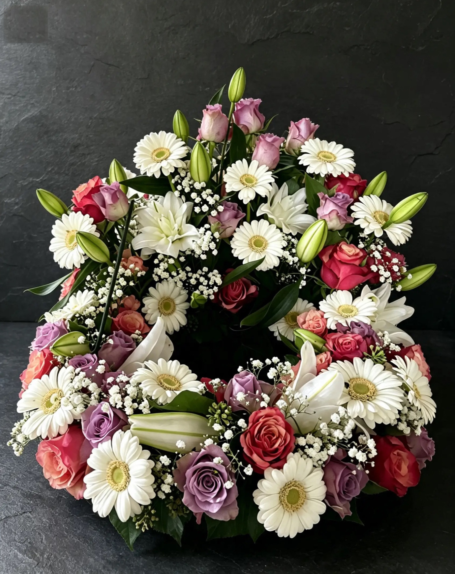 Erhöhter Urnenkranz mit Lilien, Gerbera und Rosen in Weiß, Rosa und Rot