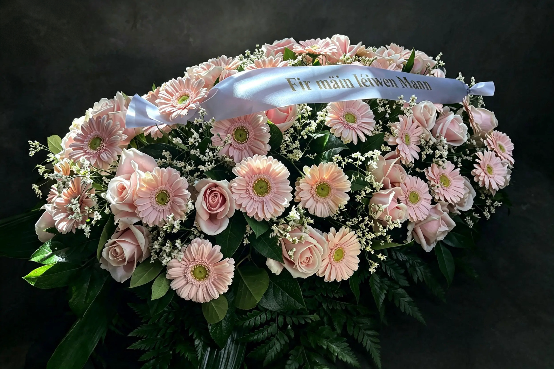Trauergebinde aus zartrosa Rosen und Gerbera mit persönlicher Schleife