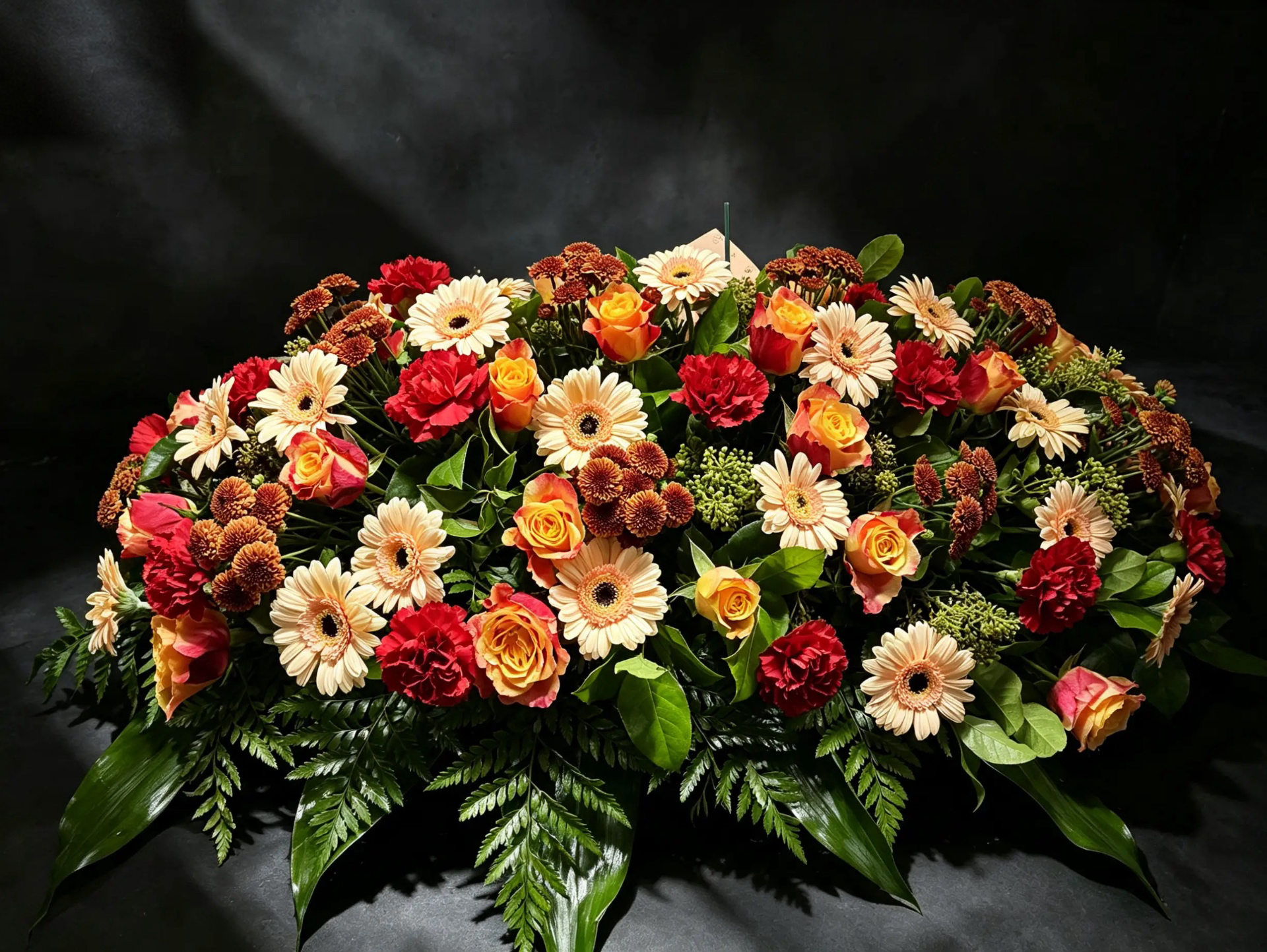 Trauergebinde in Rot, Orange und Creme mit Rosen, Gerbera und Nelken