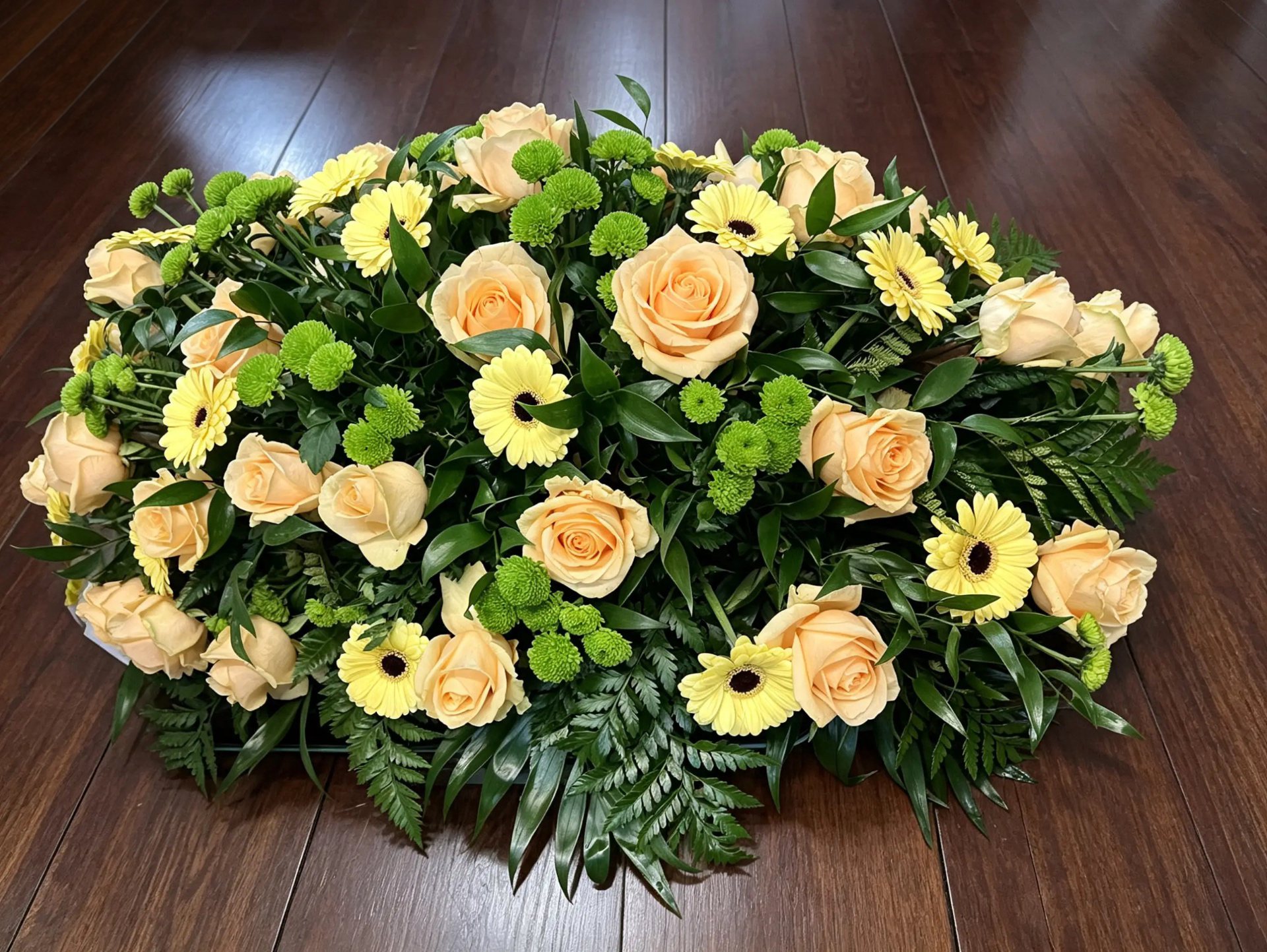 Trauergebinde aus apricotfarbenen Rosen, gelben Gerbera und grünen Chrysanthemen
