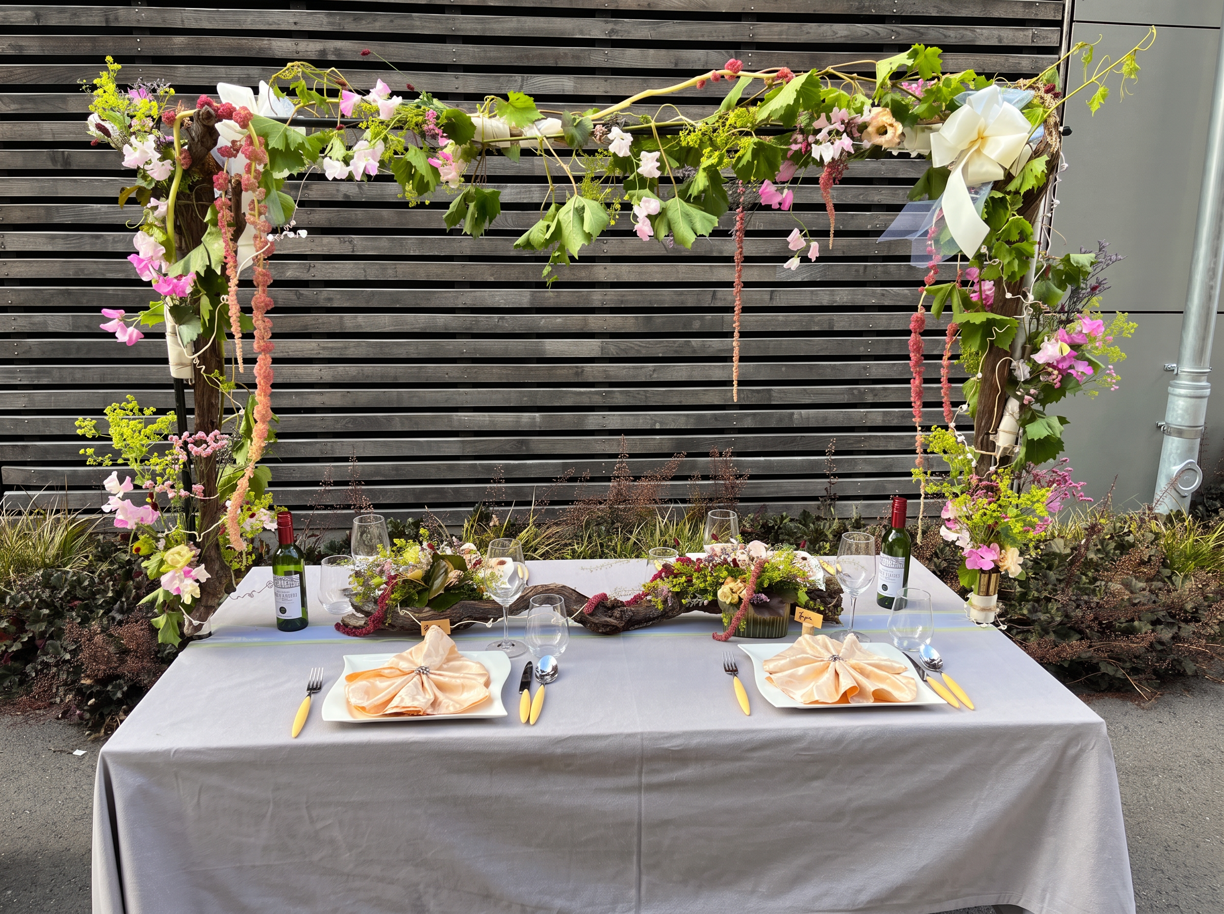 Umgesetzter Hochzeitstisch mit floralem Weinrebenbogen